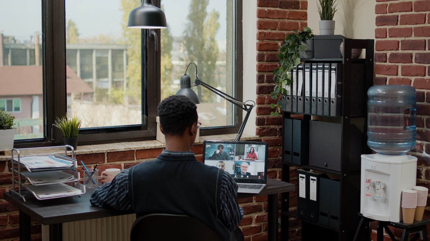 woman leaning against a couch looking at a laptop